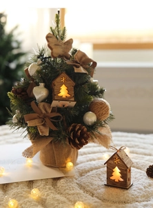 Mini tabletop Christmas tree with glowing wooden house, pine cones, and burlap base decor