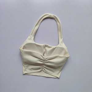 Close-up of cream halter neck sports bra featuring center ruched detail and soft knit fabric