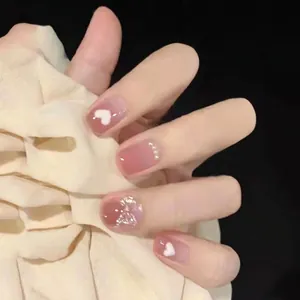 Short press-on nails with nude pink base, white hearts, pearls and glittery bows