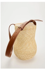 Detail of straw bucket bag showing natural fiber texture and brown leather strap