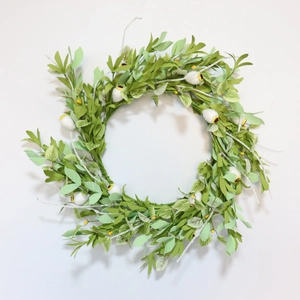 Detailed view of the artificial green leaf wreath with white fuzzy buds and yellow centers