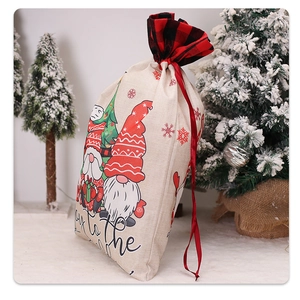 Close-up of Christmas gnome gift bag with red plaid trim and drawstring against snowy tree
