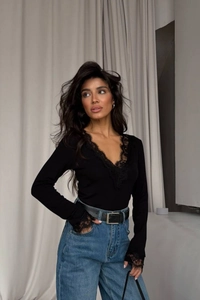 Detail of elegant black lace trim on the neckline and sleeves of a slim-fit knitted top