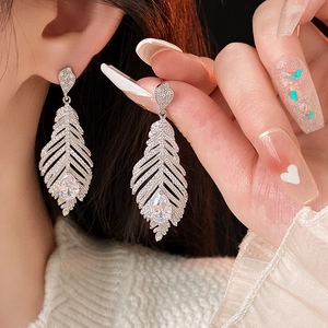Vue macro de boucles d'oreilles plume en argent avec glands en zircon et gemmes en goutte