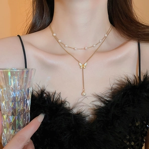 Dettaglio della collana a farfalla dorata con perle sul collo della modella