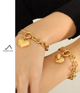 Detailed close-up of a chunky 18K gold plated Cuban chain heart bracelet on a wrist