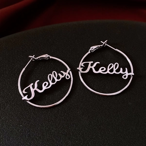 Macro view of silver hoop earrings featuring custom Kelly name script in cursive design