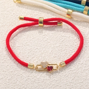 Detail of red rope bracelet with gold heart charms and adjustable pull-string closure