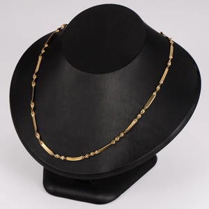 Minimalist gold snake chain necklace with textured blade links on black mannequin