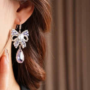 Close-up of elegant bow butterfly earring with purple teardrop zircon on model
