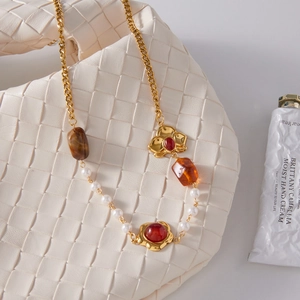 Dettaglio di collana vintage con resina ambrata, perle ed elementi floreali dorati