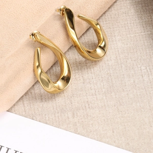 Macro shot of gold-plated irregular twisted earrings on a beige velvet holder