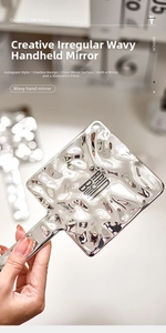 Detailed view of creative silver wave-shaped handheld mirror with metallic liquid texture