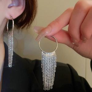 Detail of silver long tassel hoop earrings with metallic fringe on model for a sleek look