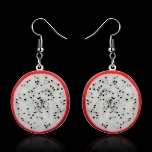 Macro shot of realistic dragon fruit slice earrings with red skin and black seeds on black background