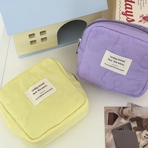 Quilted cloud-patterned cosmetic pouches in yellow and purple with zipper closure