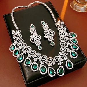 Detail of luxury teardrop emerald and zircon necklace and earrings set on black jewelry box