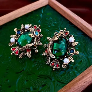 Vintage emerald and pearl earrings in gold filigree setting on a decorative tray
