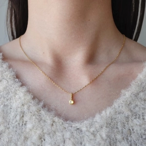 Dettaglio della collana con pietra portafortuna in oro e pendente in zircone