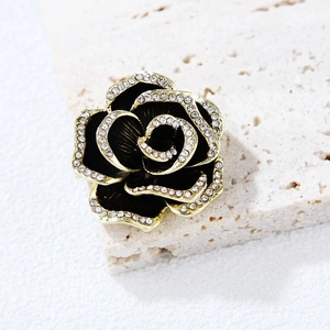 Macro della spilla a camelia vintage con smalto nero e strass luccicanti