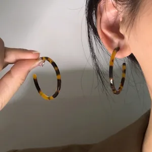 Close-up of tortoise shell pattern acrylic C-shaped hoop earrings worn on ear