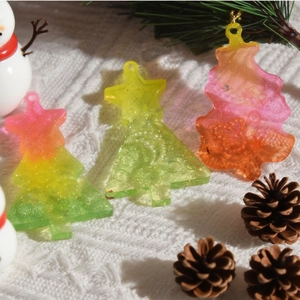 Macro shot of translucent resin Christmas tree pendants with fine glitter and hang holes