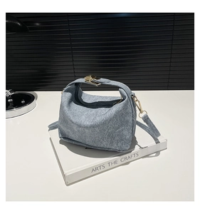 Detail of grey-blue pleated handbag with gold buckle closure and denim-like texture