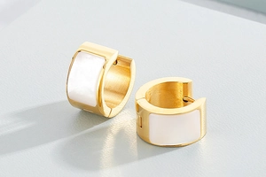 Close-up of golden chunky hoop earrings featuring elegant white shell rectangular inlays