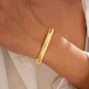 Close-up of 18k gold plated bangle featuring fine horizontal textures on woman wrist