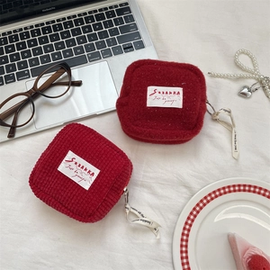 Cute red corduroy and plush square coin purses with ribbon zippers on a white desktop