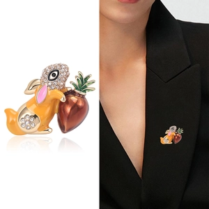 Golden bunny brooch with orange enamel and crystal stones holding a carrot on a suit