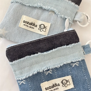 Detail eines Denim-Kartenhalters mit Fransenrand und gesticktem weißem Schleifen-Dekor