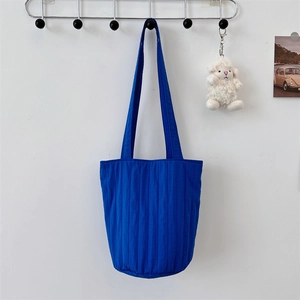 Detalle del bolso de cubo azul Klein plisado con textura vertical y adorno blanco