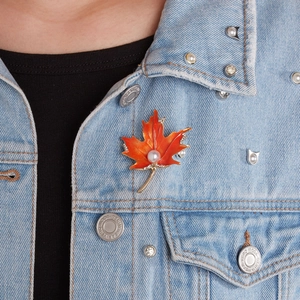 Elegant orange maple leaf brooch with pearl and rhinestones on a denim jacket