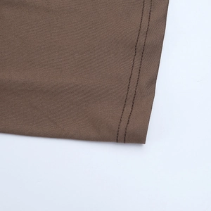 Gros plan des doubles coutures sur l'ourlet de la robe longue en maille marron foncé