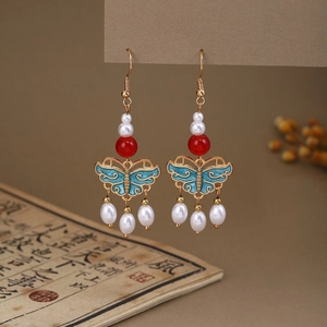Detail of blue butterfly drop earrings with white pearls and red beads in vintage style