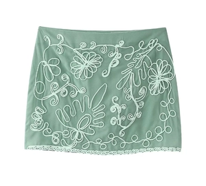 Detail of sage green fabric with white floral rope embroidery and vine pattern accents