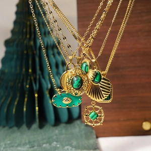 Gros plan de colliers en or 18K avec pendentifs en malachite verte sur bois rétro