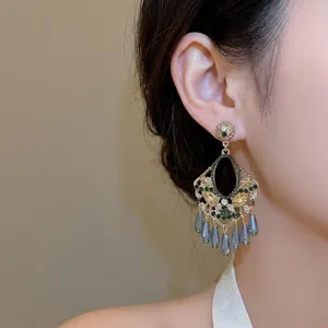 Vintage gold tassel earrings with colorful rhinestones and blue crystal drops on model