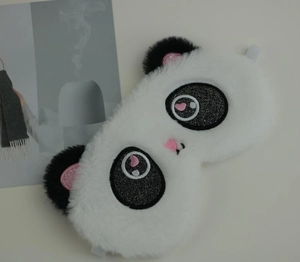 Detail of plush panda sleep mask featuring embroidered sequins and soft faux fur texture