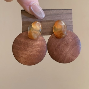 Macro shot of geometric wooden earring with amber resin detail and natural grain texture