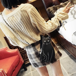 Cute black cat shaped crossbody bag with metal chain strap worn by a female model
