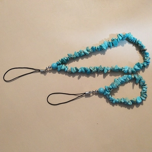 Turquoise stone beaded phone charms with silver metal fittings on beige background
