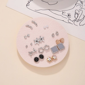 Flat lay of multiple stud earrings set with pearls and crystals on a pink round pad