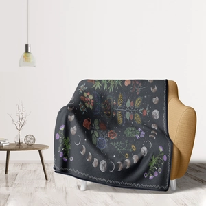 Detail of soft charcoal grey flannel blanket with floral and moon phase patterns on armchair