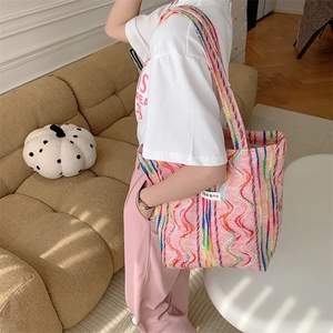 Détail du sac cabas en toile à rayures arc-en-ciel avec broderie et étiquette tissée