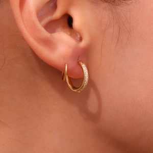 Vue détaillée de boucles d'oreilles spirales dorées avec un anneau lisse et un pavé de zircons