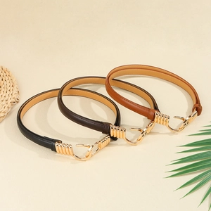 Detailed view of black and brown leather thin belts with golden metal hooks on beige texture