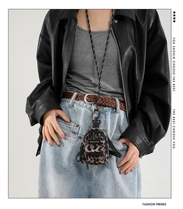 Detailed view of mini leopard print crossbody bag with woven lanyard on model