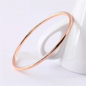 Detail of thin 2mm rose gold plated stainless steel bangle resting on a white cup